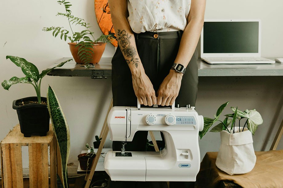 mujer sosteniendo una maquina de coser