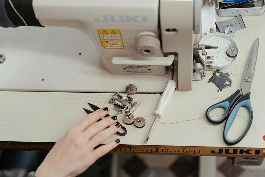 mujer en una maquina de coser recta con un cortahilachas