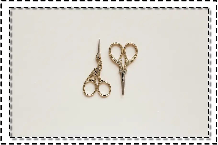 Tijeras de sastre doradas sobre fondo blanco, herramientas clásicas para el corte de telas.