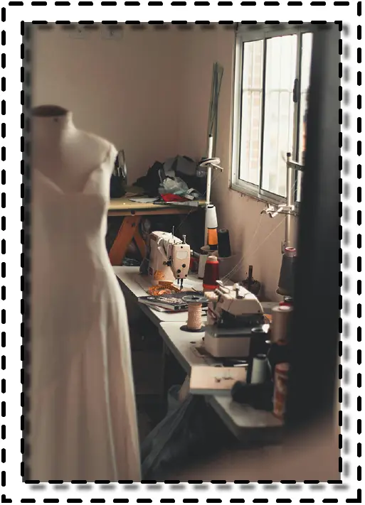Taller de costura con maniquí y máquinas de coser junto a una ventana iluminada.