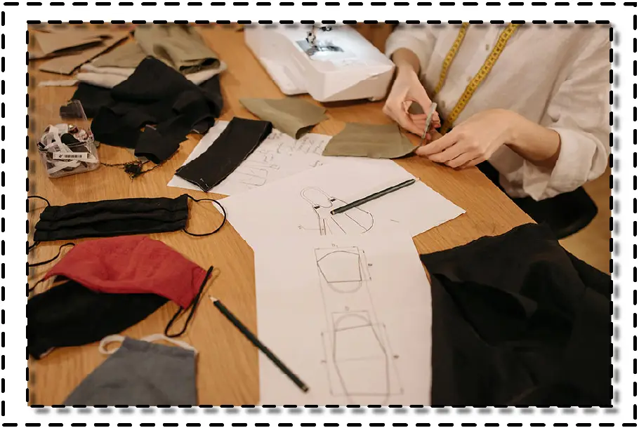 Diseñadora trabajando sobre una mesa con telas, moldes y dibujos técnicos de patrones, representando el proceso creativo previo a la digitalización.