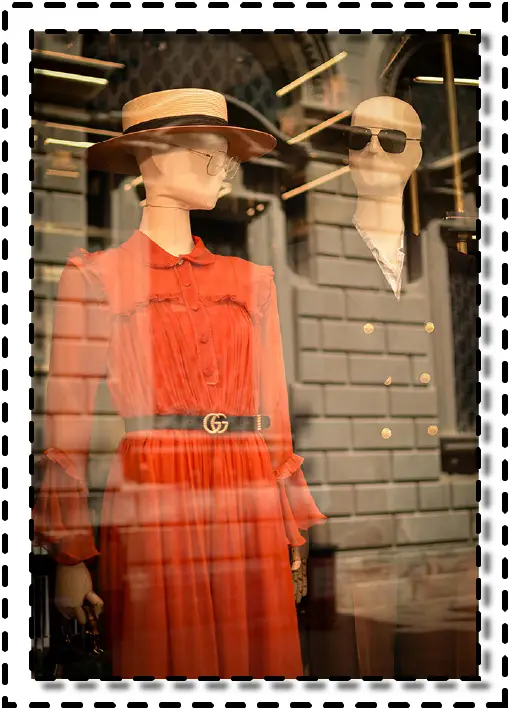 Vitrina de tienda con maniquíes vestidos con prendas elegantes y reflejo urbano.