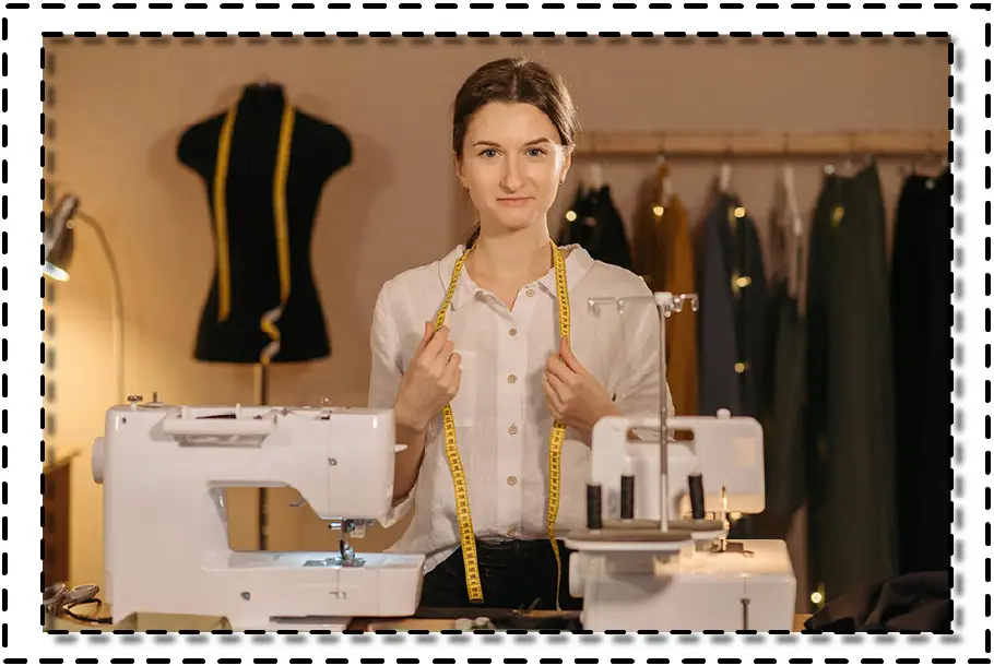 Mujer joven con cinta métrica en el cuello, frente a una máquina de coser, lista para comenzar su jornada de costura.