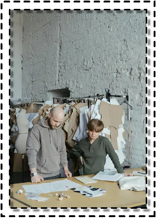 Personas revisando planos de diseño y patrones de ropa en un taller textil moderno.
