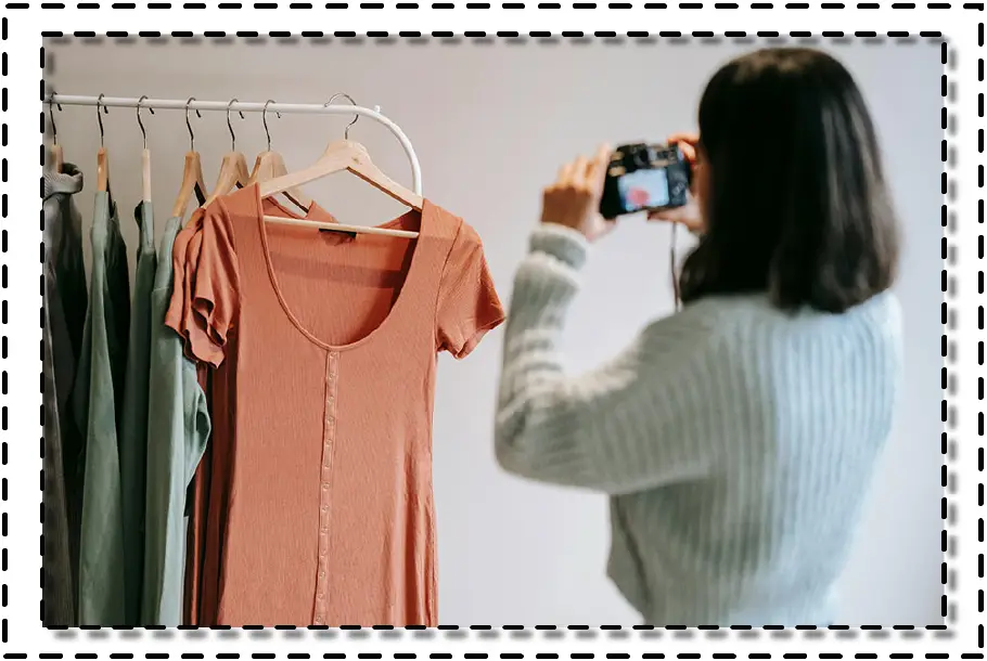 Mujer fotografiando una prenda colgada en percha, como parte del registro de diseño o presentación de colección.