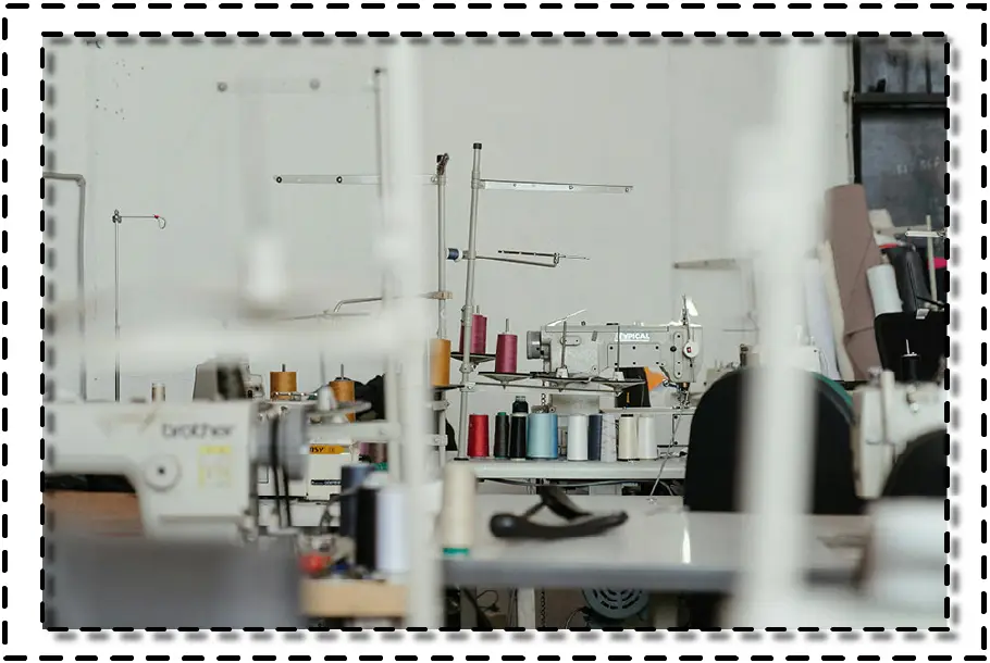 Máquinas de coser industriales con conos de hilo de colores en taller textil.